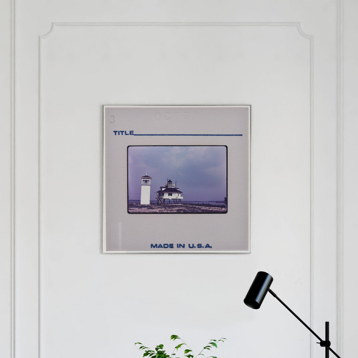 a framed photograph of a lighthouse on a white wall.