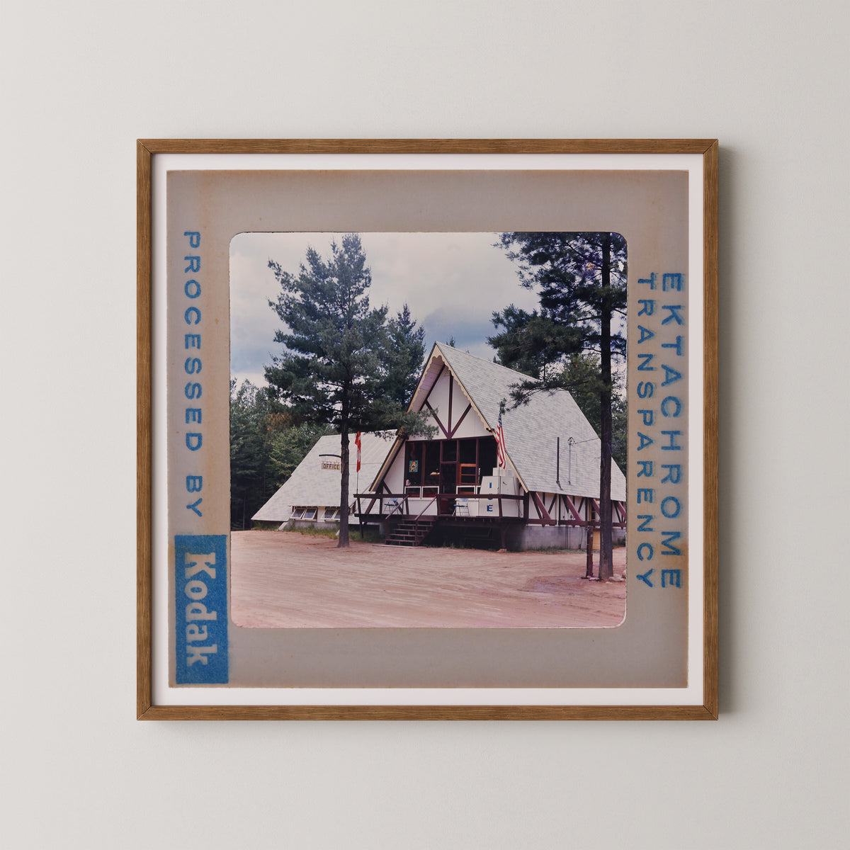 A framed photograph of a white triangular building with a red roof, surrounded by trees, with the text "Kodak" visible in the frame.