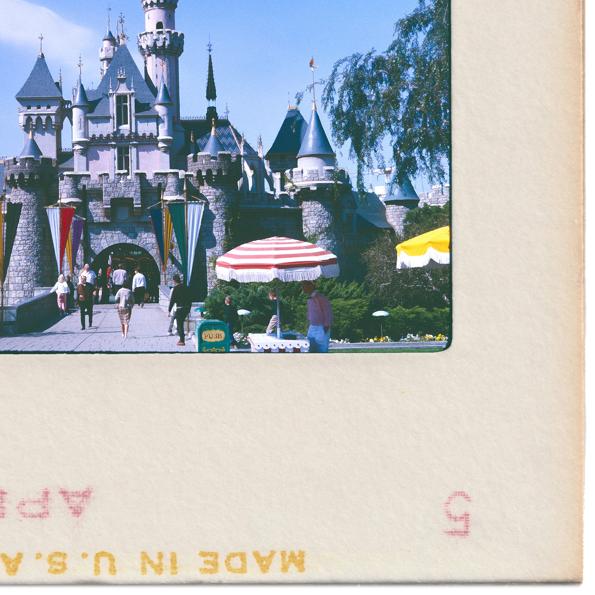 A large castle with multiple towers and turrets, surrounded by trees and people walking around.