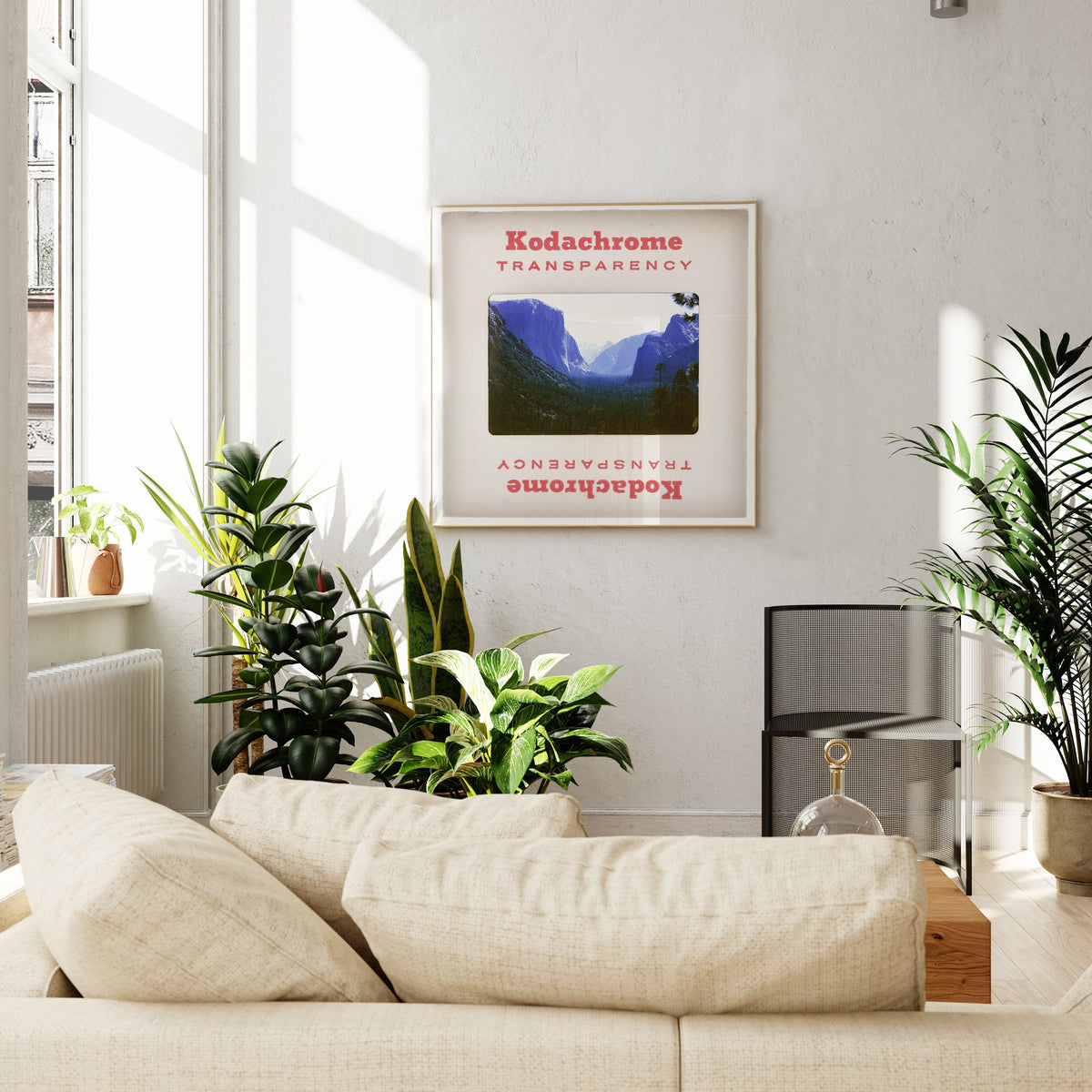 a cozy living room with a beige sofa, a framed poster of a mountain landscape, and several potted plants.