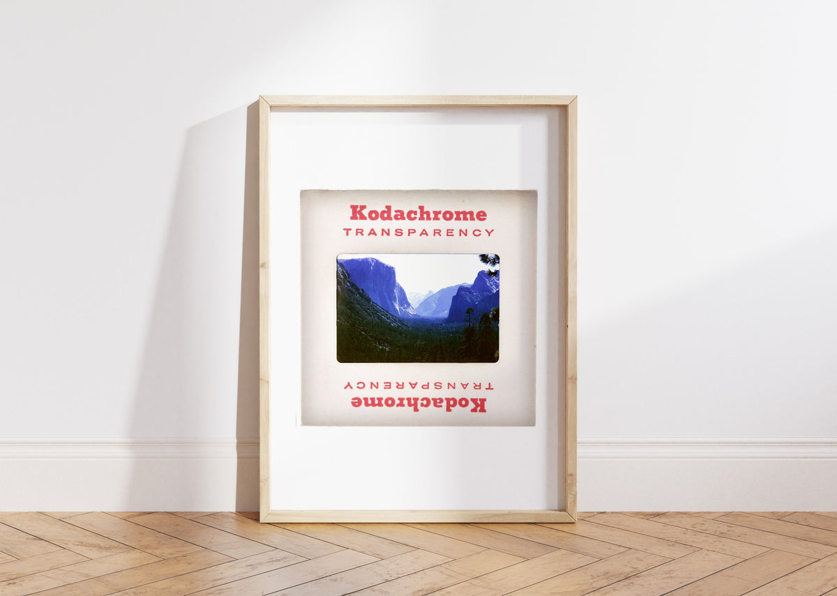 A framed photograph of a mountainous landscape, with the text "Kodachrome Transparence" and "Kodachrome Transparence" repeated on the frame.