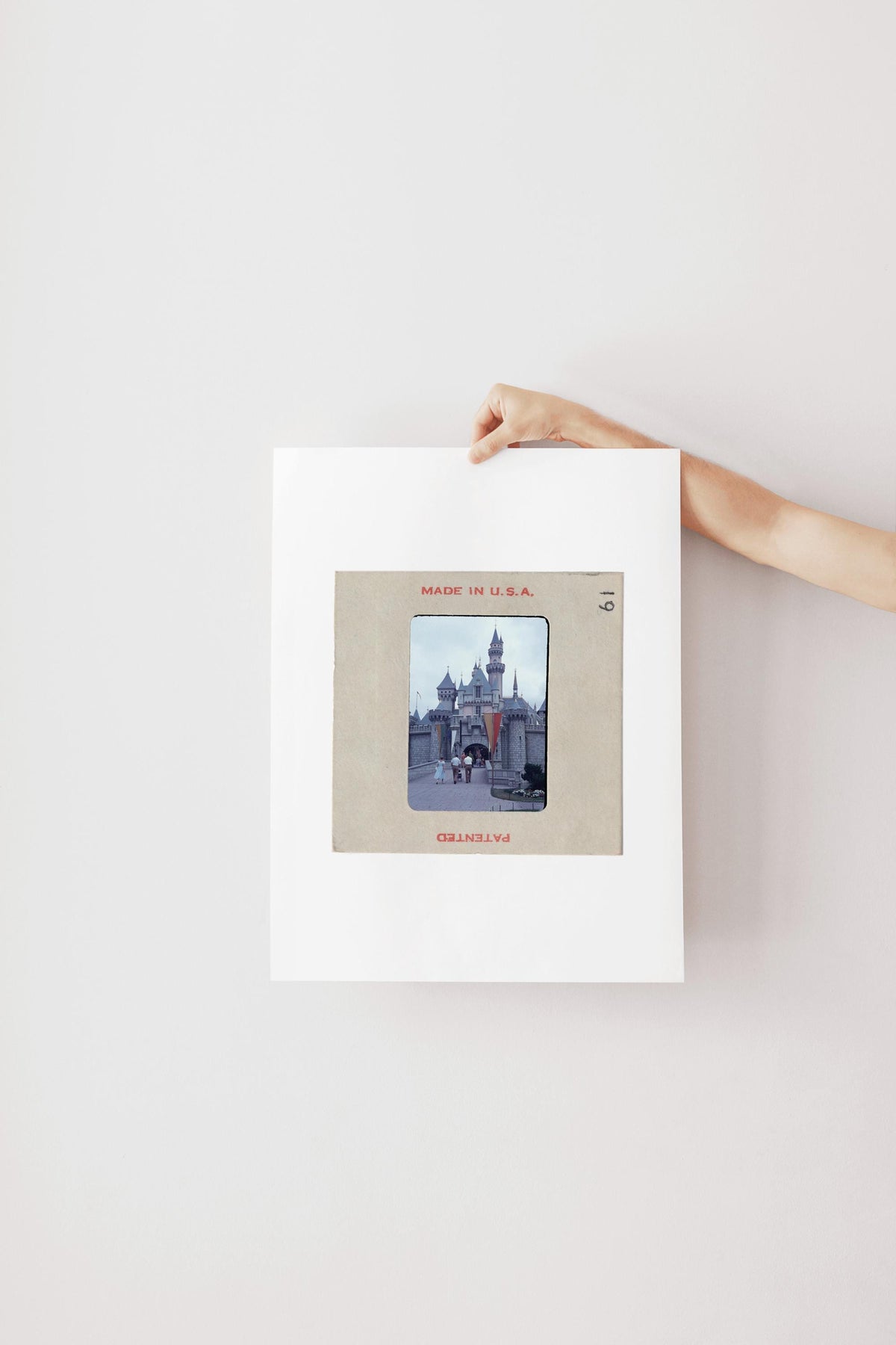 A person's hand is holding a framed photograph of a castle or palace, with the text "MADE IN U.S.A." visible on the frame.
