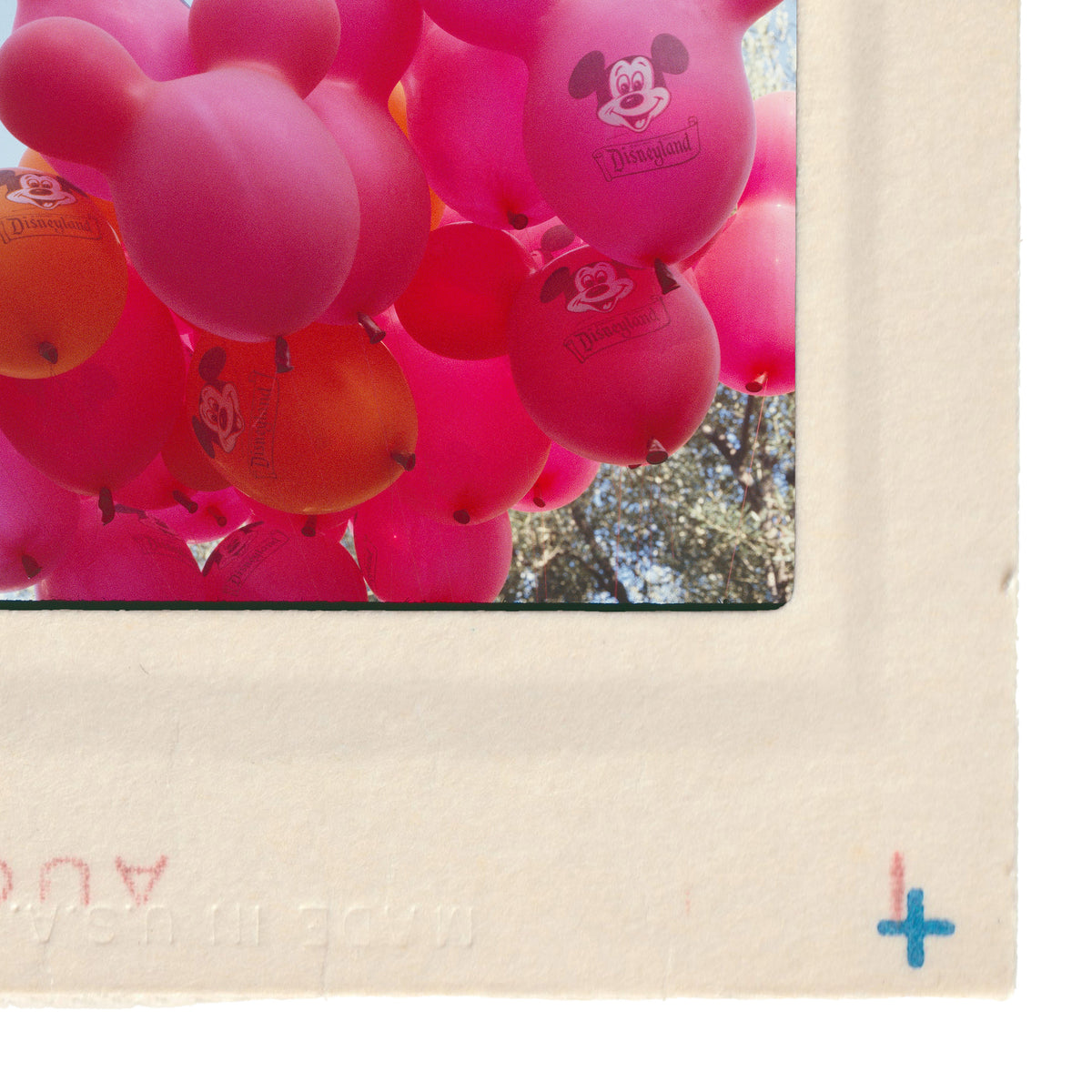 a collection of pink and orange balloons, with some featuring Mickey Mouse designs, floating in the air.