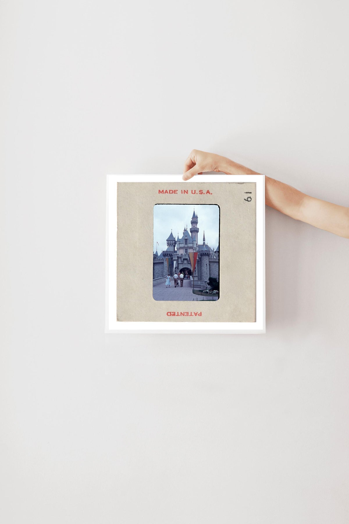 A person's hand is holding a framed picture of a castle or palace, with the text "MADE IN U.S.A." visible on the frame.