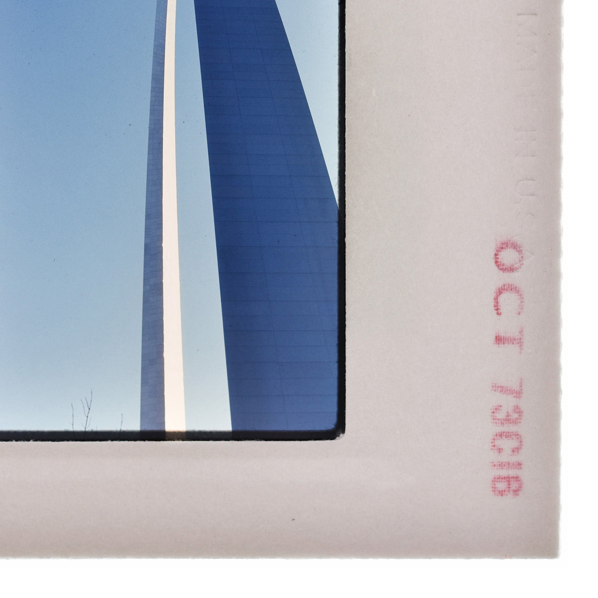 a close-up view of a white frame with a blue and white striped structure, possibly a building or monument, reflected in it.