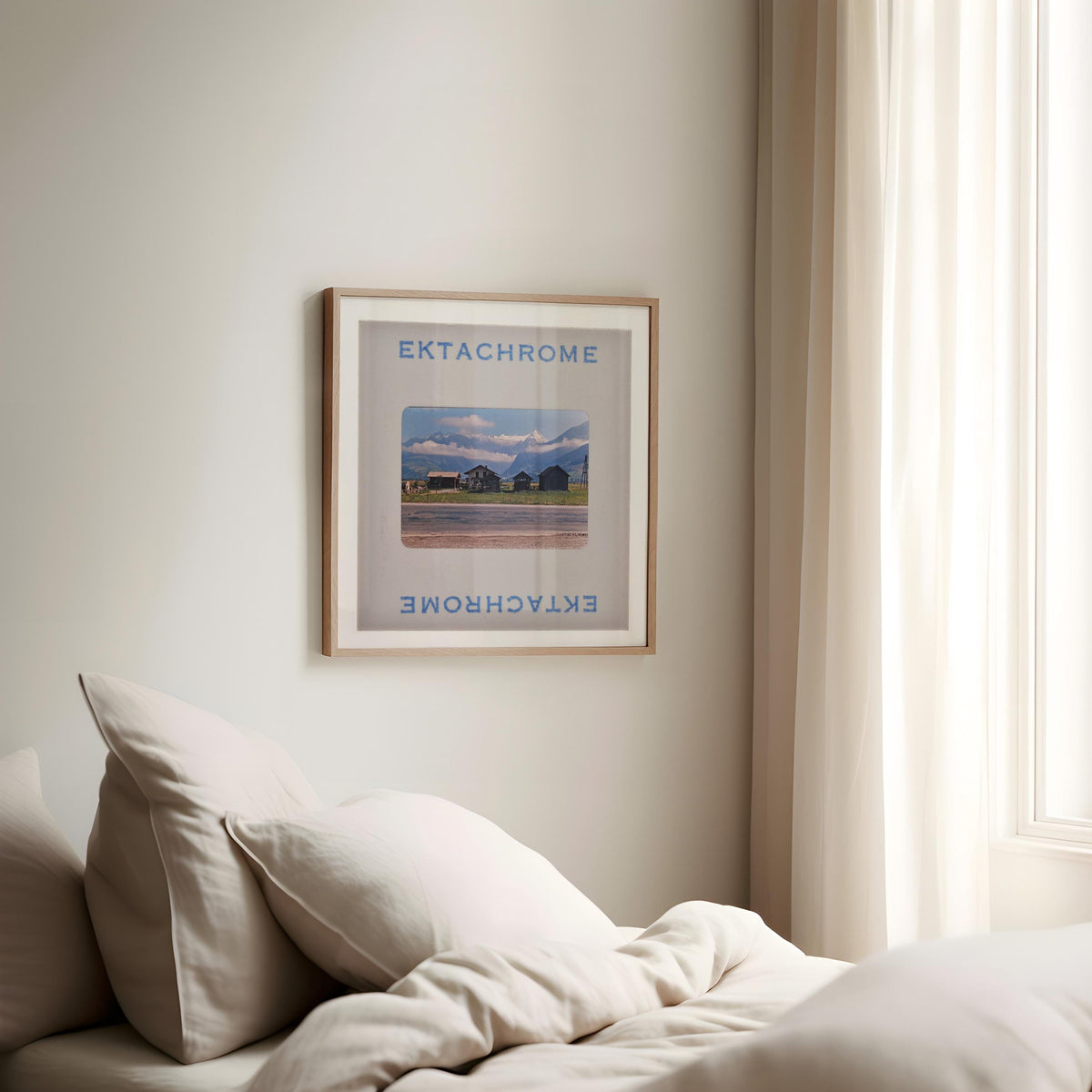 a framed poster of a scenic landscape hanging on a wall, with a bed with white pillows in the foreground.