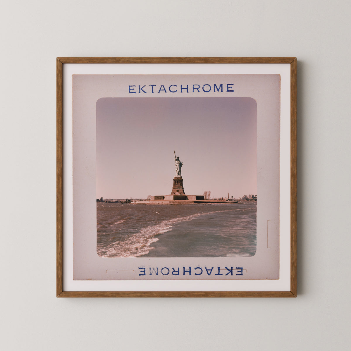 a framed photograph of the Statue of Liberty on the shore of the Hudson River.