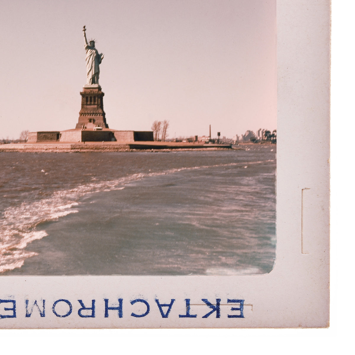 the Statue of Liberty standing on a small island in the harbor, with the ocean in the background.