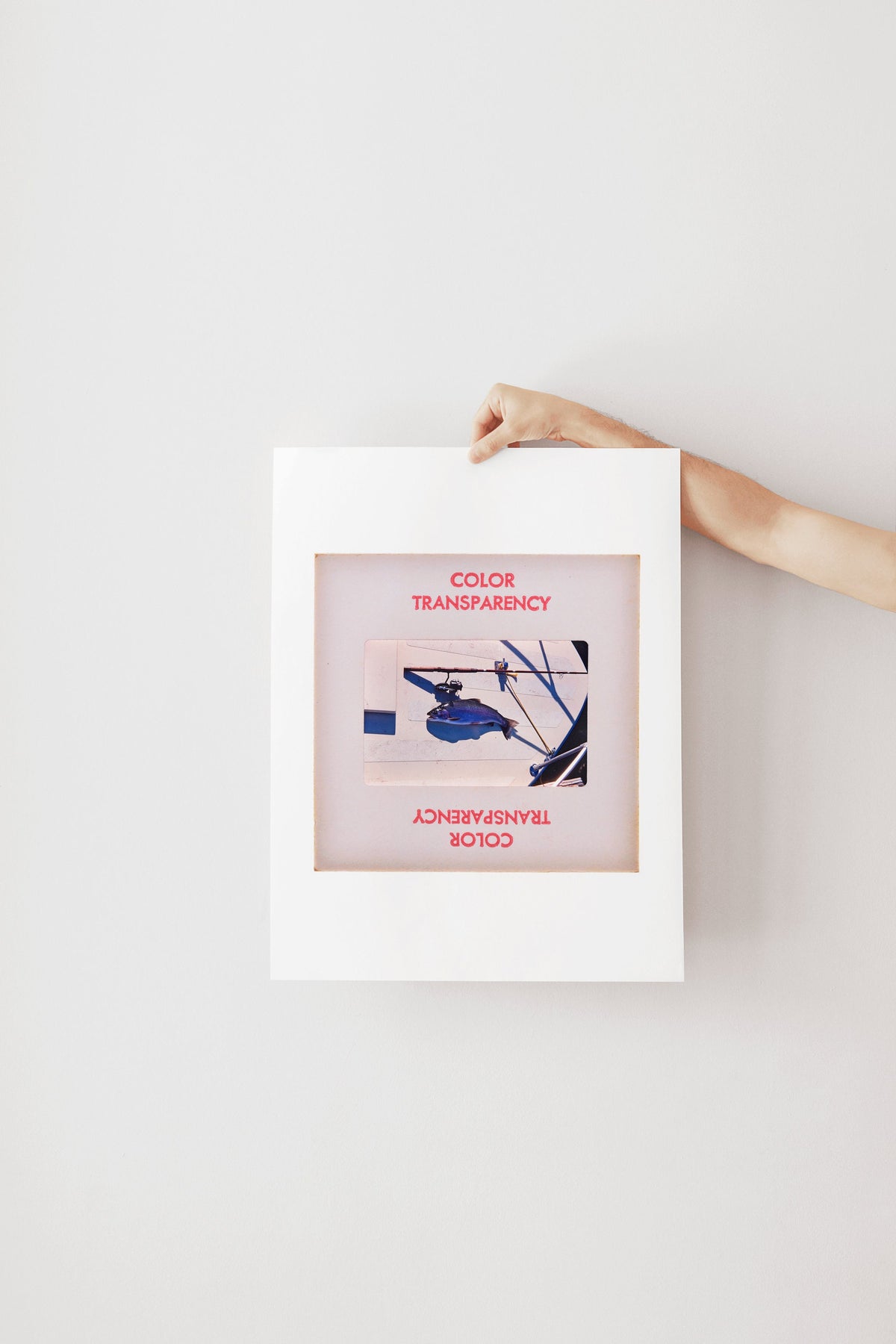A hand is holding a white frame with a framed image of a blue and white abstract artwork.