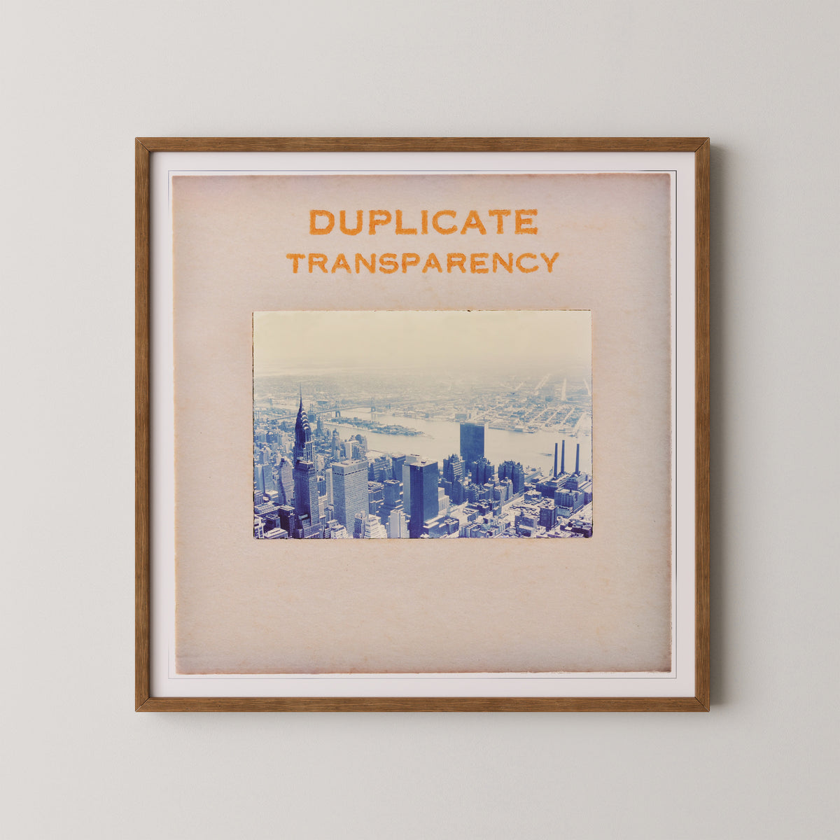 The image is a framed print of a cityscape, with the text "DUPLICATE TRANSPARENCY" prominently displayed above the photograph.