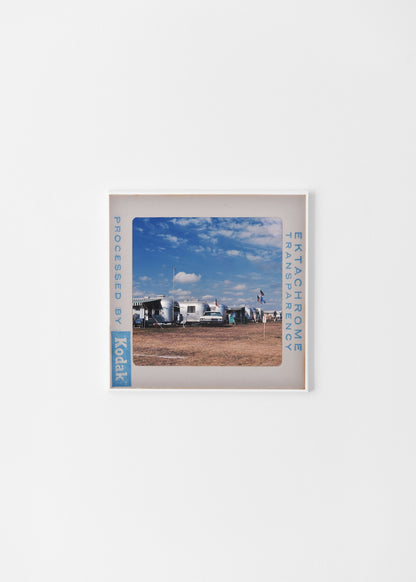 A framed photograph of a beach scene with a clear blue sky and a few people enjoying the day.