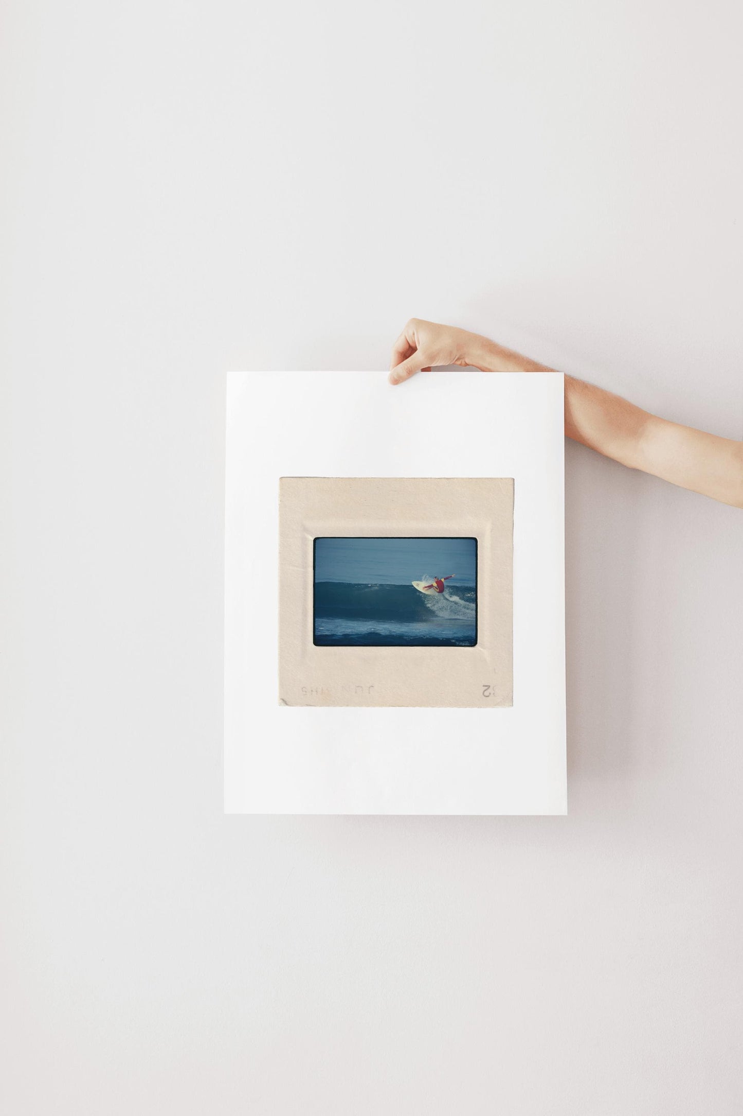 Vintage 1970s Kodachrome slide photograph of a surfer in a red and yellow competition jersey carving off the top of a deep blue wave along the California coast, with white spray exploding from the board. Printed as a giclée fine art print on archival matte paper.