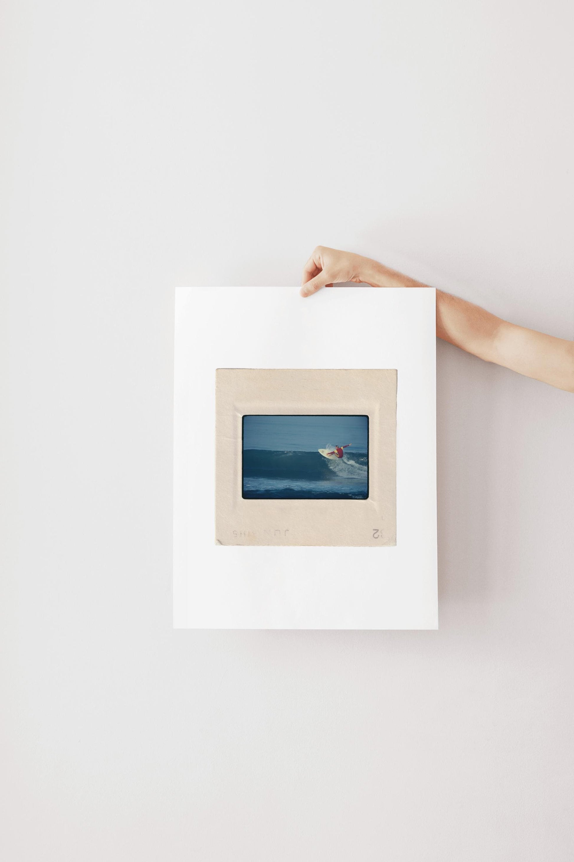 Vintage 1970s Kodachrome slide photograph of a surfer in a red and yellow competition jersey carving off the top of a deep blue wave along the California coast, with white spray exploding from the board. Printed as a giclée fine art print on archival matte paper.