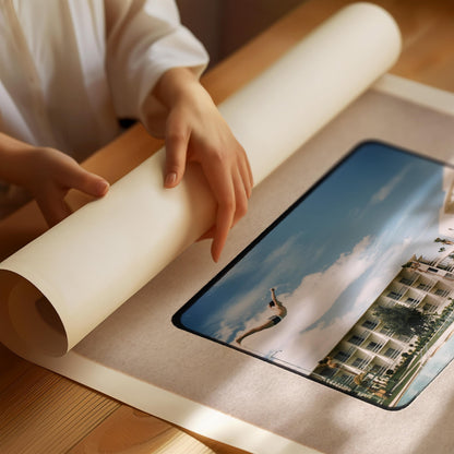 A person's hands are holding a roll of paper over a framed photograph of a tropical resort, with palm trees and a clear blue sky visible in the image.