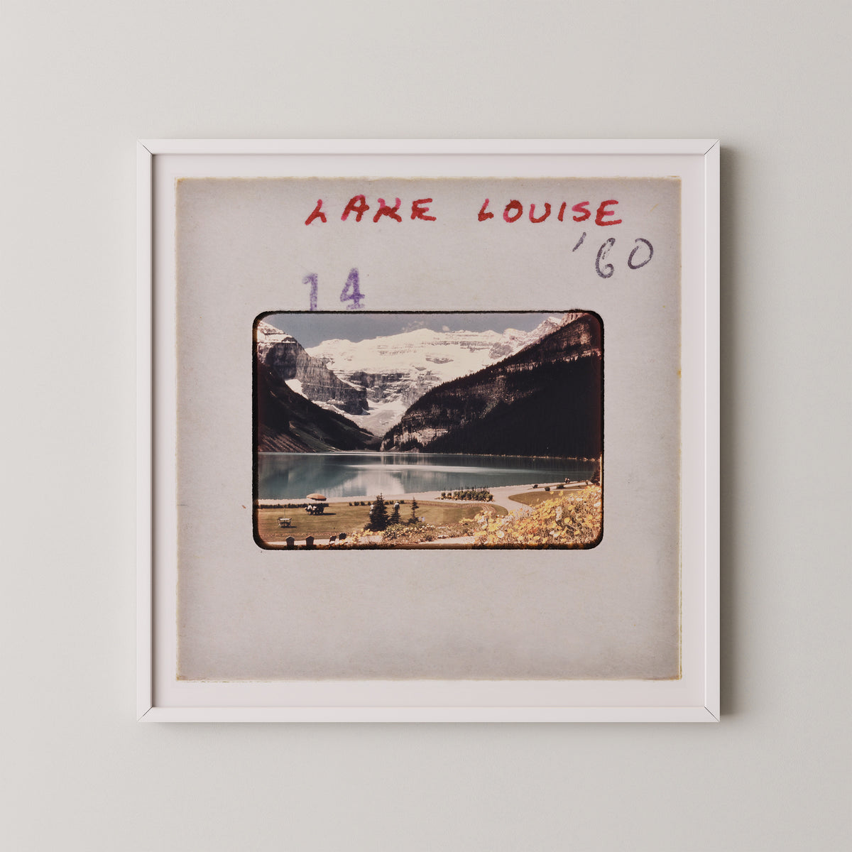 The image is a framed photograph of a scenic mountain landscape with a lake and snow-capped peaks in the background.