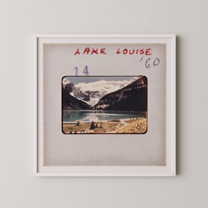 The image is a framed photograph of a scenic mountain landscape with a lake and snow-capped peaks in the background.