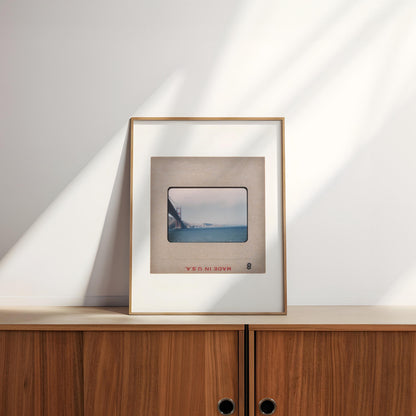 A framed photograph of a bridge is displayed on a wooden cabinet against a white wall.