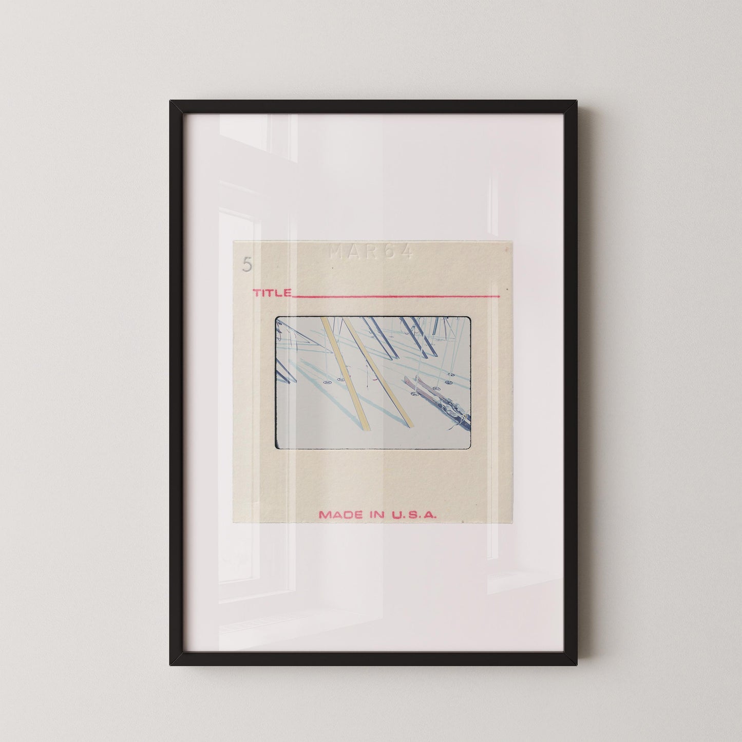 The image is a framed artwork depicting a collage of various images, including a photograph of a pair of scissors. The artwork is titled "MADE IN U.S.A." and is displayed on a white wall.