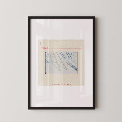 The image is a framed artwork depicting a collage of various images, including a photograph of a pair of scissors. The artwork is titled "MADE IN U.S.A." and is displayed on a white wall.
