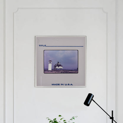 a framed photograph of a lighthouse on a white wall.