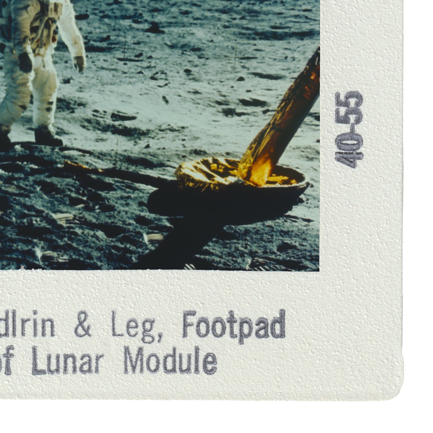 a person walking on the lunar surface, with a large object, possibly a tool or equipment, in their hand.