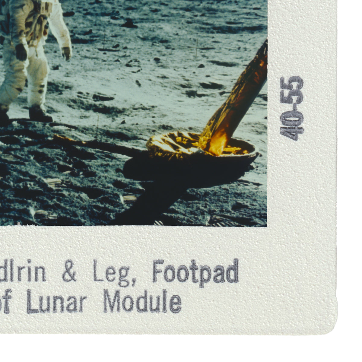 a person walking on the lunar surface, with a large object, possibly a tool or equipment, in their hand.