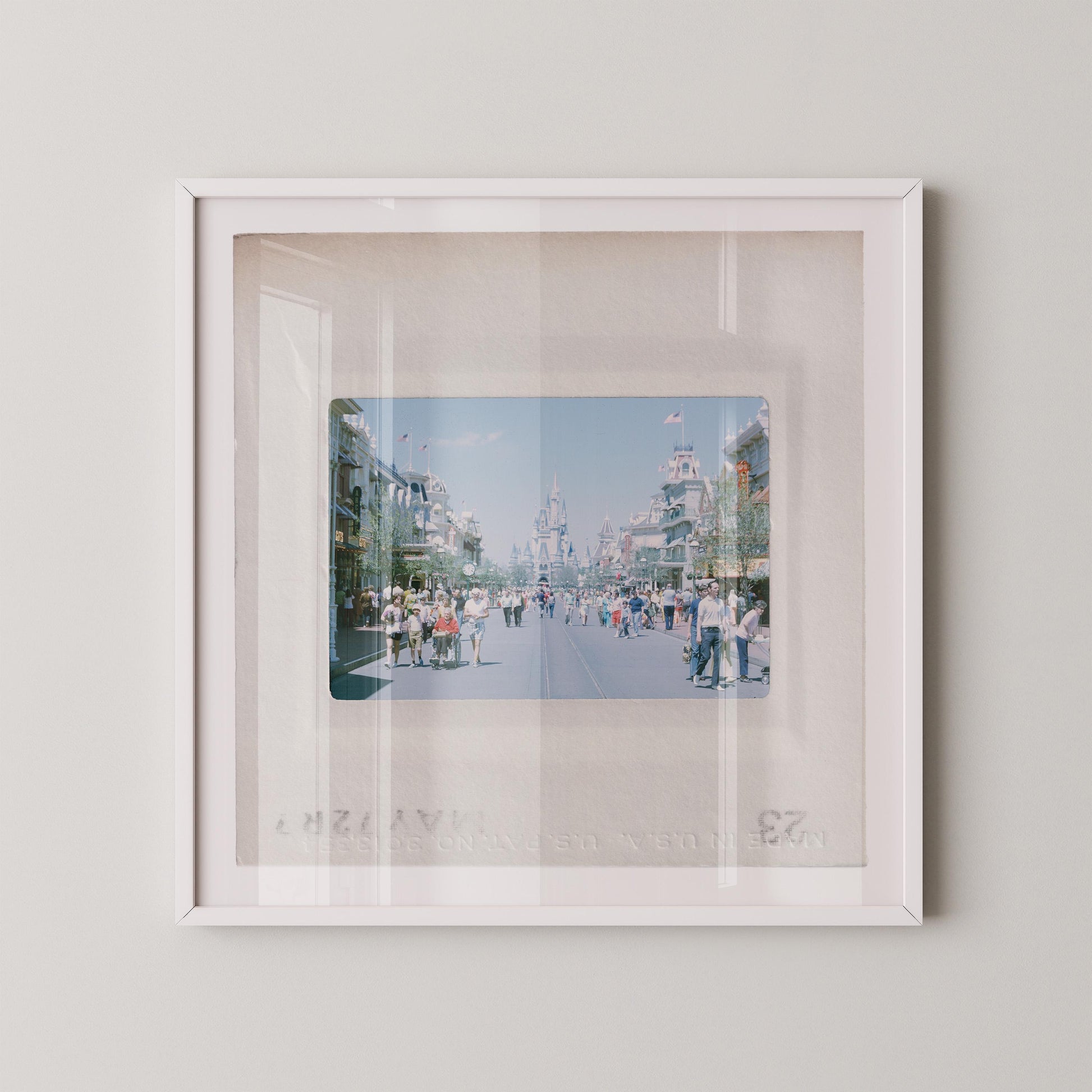 A framed photograph of a busy street scene with people walking and buildings in the background.