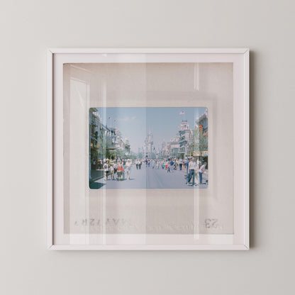 A framed photograph of a busy street scene with people walking and buildings in the background.