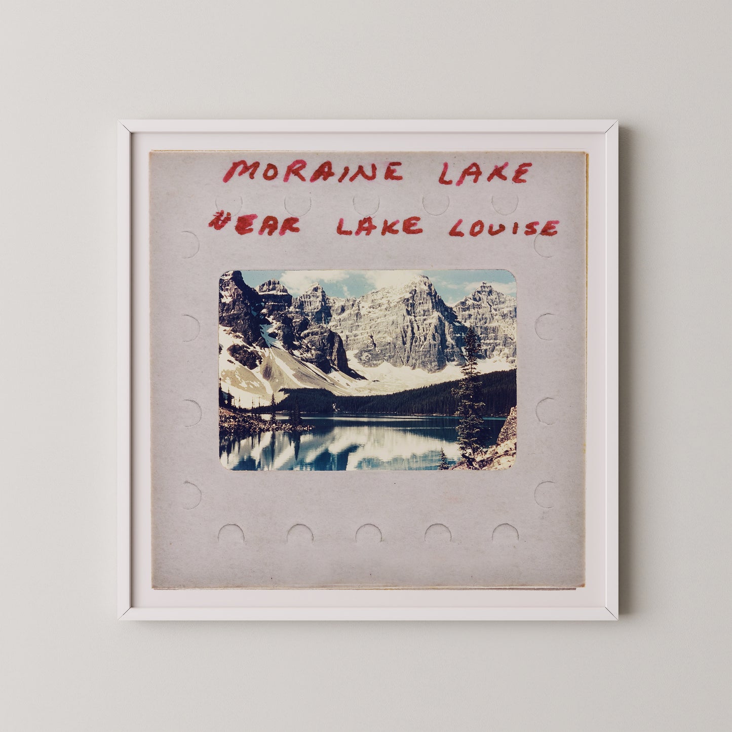 The image is a framed photograph of a scenic mountain landscape, with a lake in the background. The text above the photograph reads "MORAIN LAKE" and "EAR LAKE LOUISE".