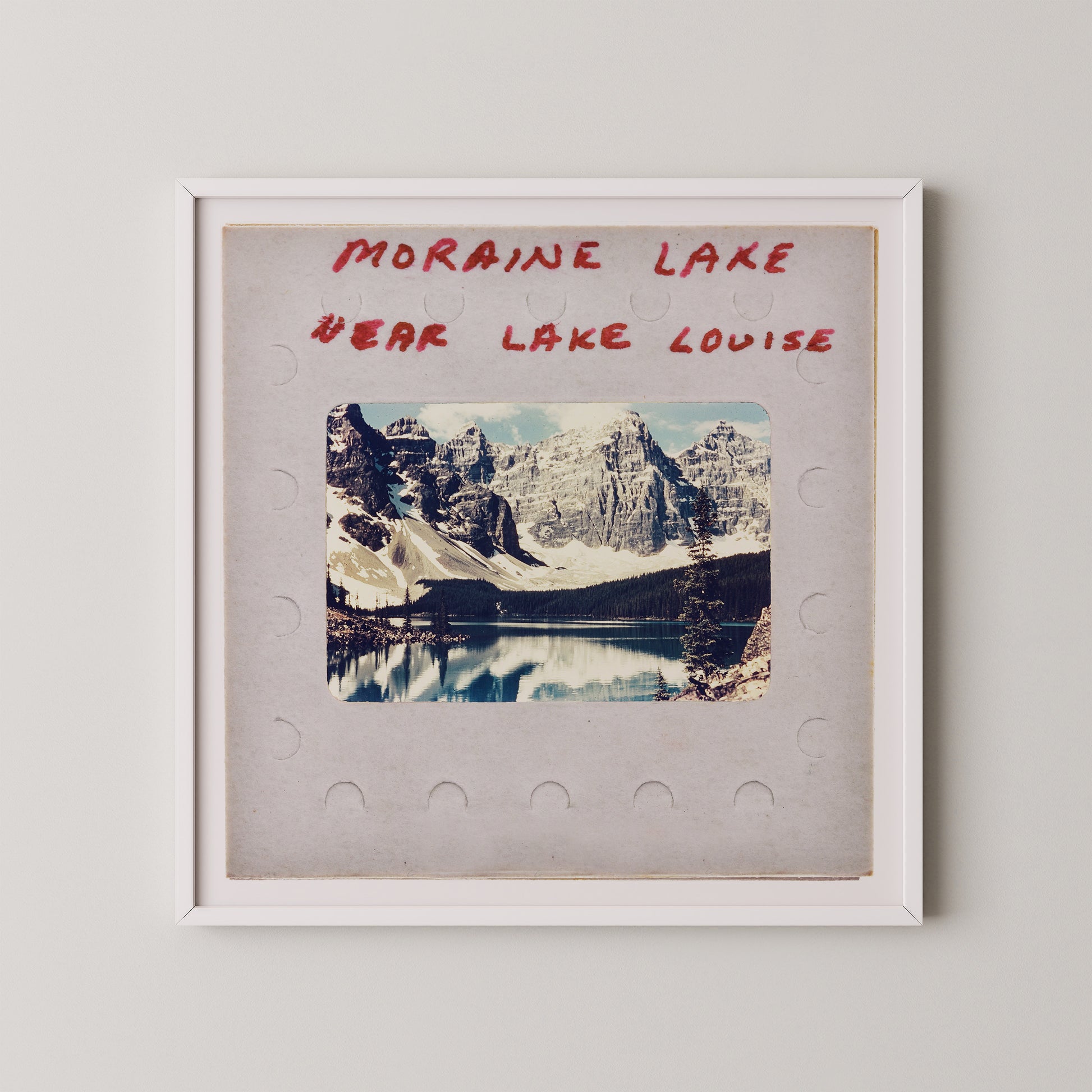 The image is a framed photograph of a scenic mountain landscape, with a lake in the background. The text above the photograph reads "MORAIN LAKE" and "EAR LAKE LOUISE".