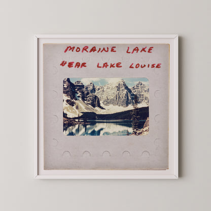 The image is a framed photograph of a scenic mountain landscape, with a lake in the background. The text above the photograph reads "MORAIN LAKE" and "EAR LAKE LOUISE".