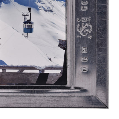 A ski lift is suspended in the air, with a snowy mountain landscape visible below.