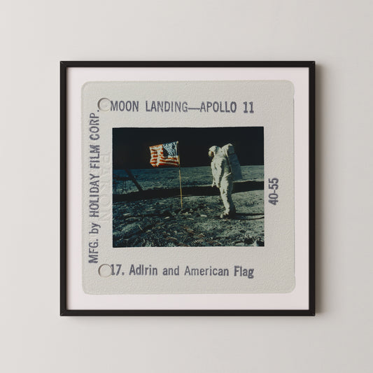 a framed photograph of the Apollo 11 moon landing, with the astronaut standing on the lunar surface holding an American flag.