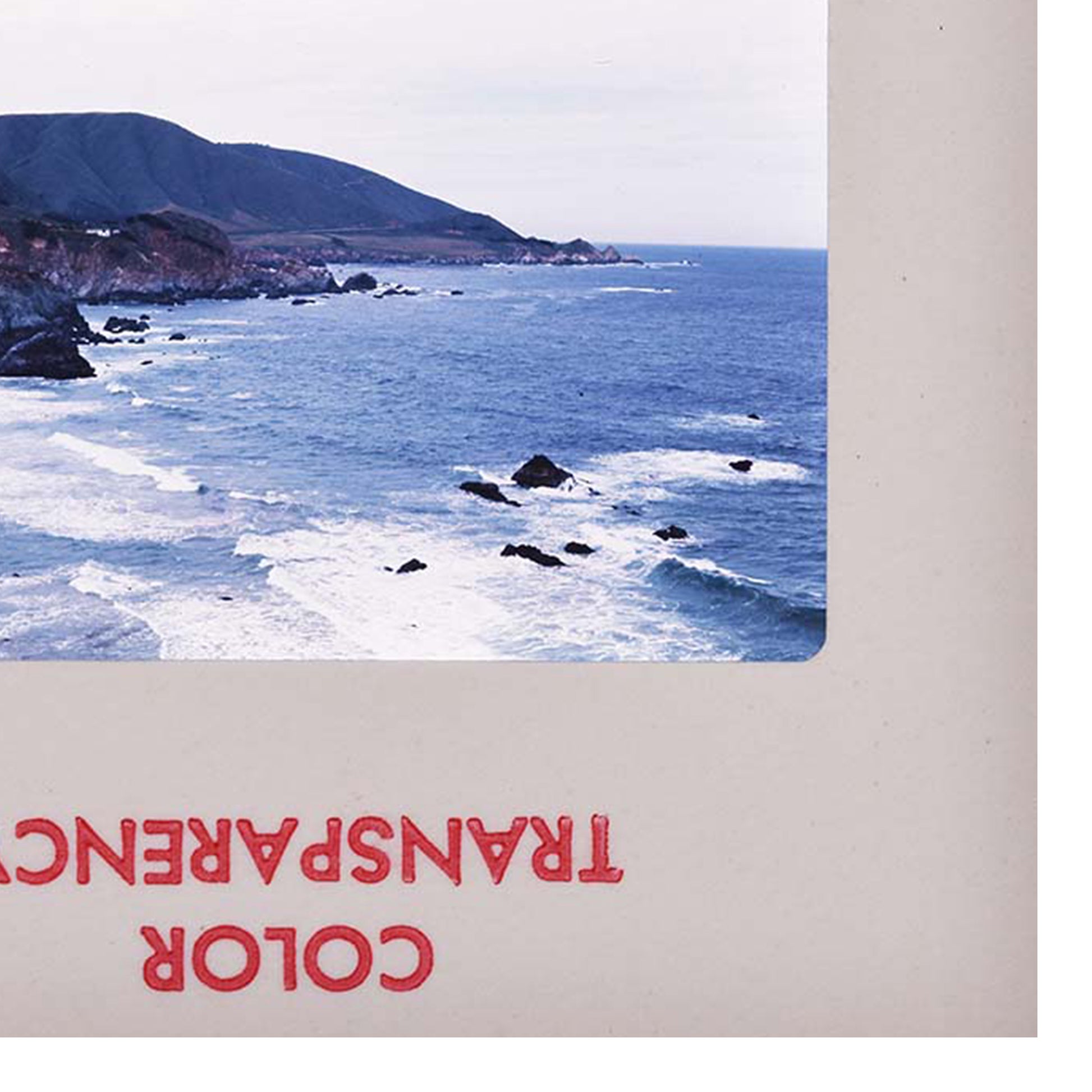 a rocky coastline with crashing waves, featuring a mountainous backdrop.