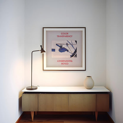 a minimalist interior design with a white wall, a wooden cabinet, a lamp, and a framed poster.