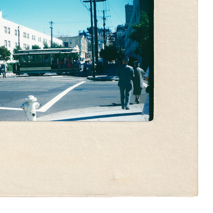 a street scene with a trolley car, a fire hydrant, and people walking on the sidewalk.