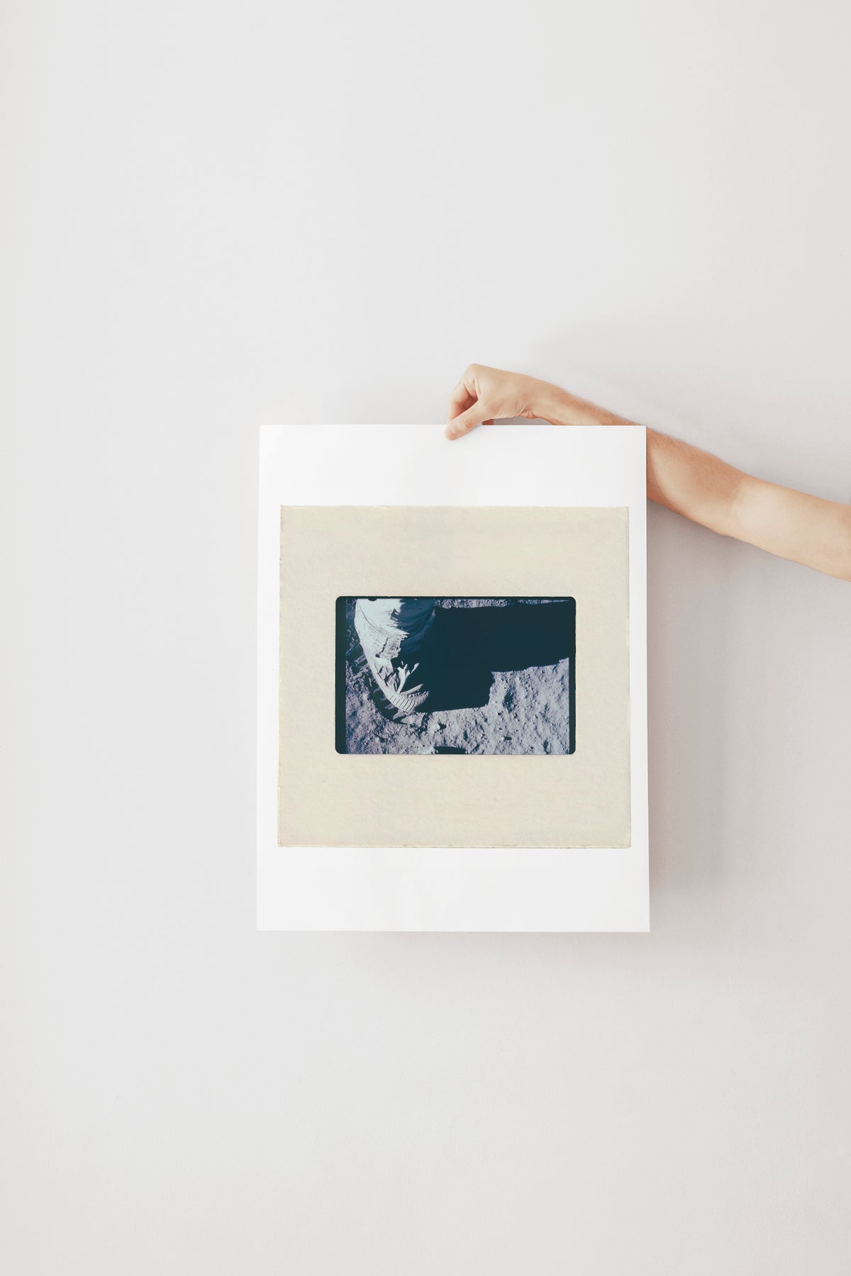 A hand is holding a framed photograph of a person's face, which appears to be a close-up of a person's face.