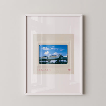 The image is a framed photograph of a train on a bridge, with a clear blue sky in the background.