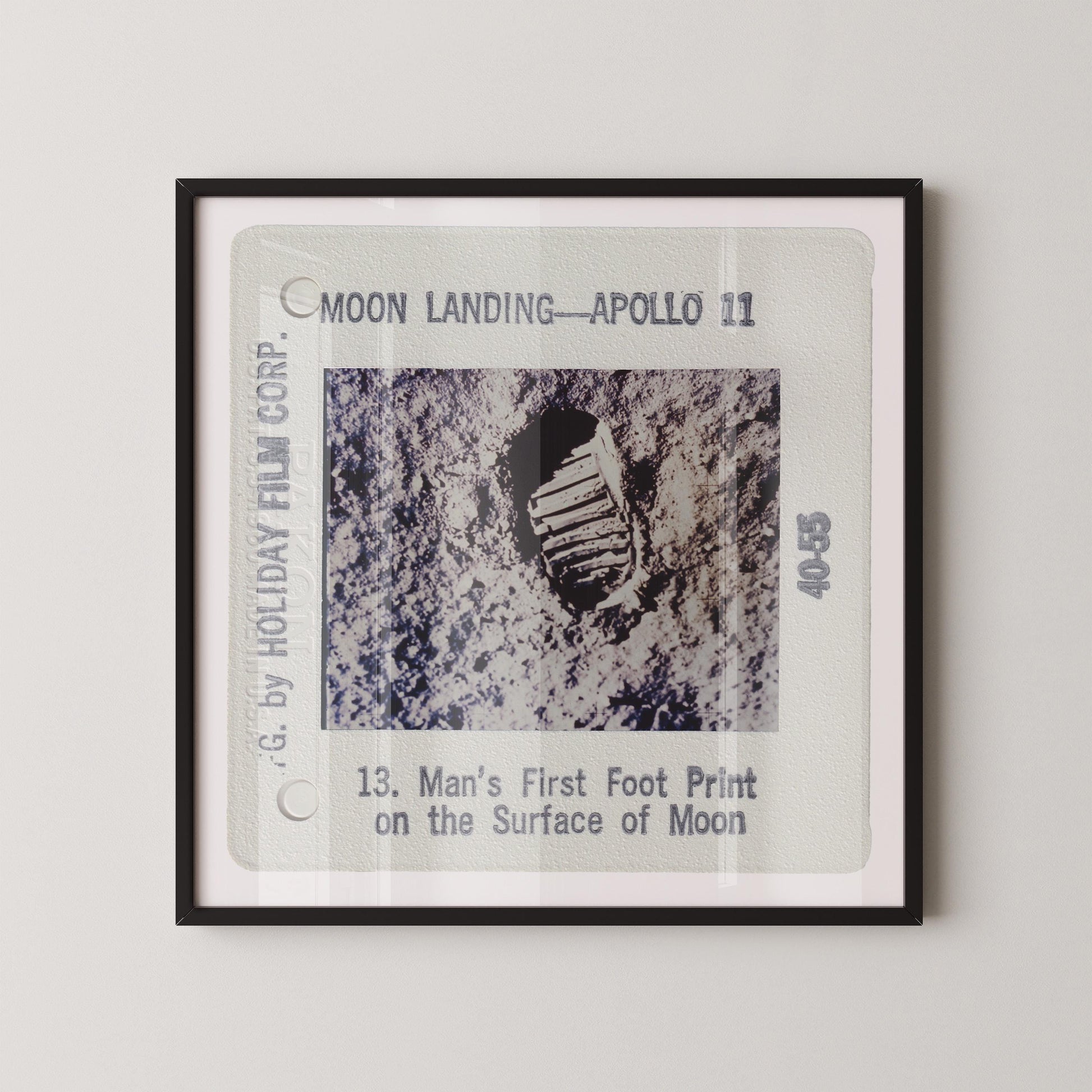 The image is a framed photograph of a man's first print on the surface of the Moon, taken during the Apollo 11 mission.