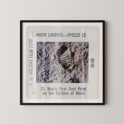 The image is a framed photograph of a man's first print on the surface of the Moon, taken during the Apollo 11 mission.