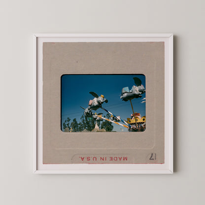 A framed slide presentation with a photograph of a carnival ride featuring a large elephant-like structure in the sky.