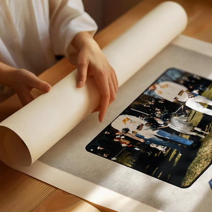 A person's hands are holding a roll of paper, which appears to be a canvas or poster, with a printed image of people on it.
