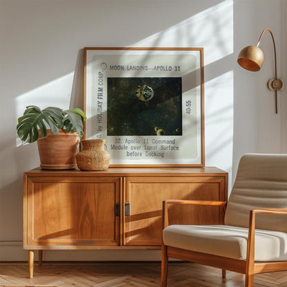 a framed photograph of the Apollo 11 moon landing, with a wooden cabinet and a beige armchair in the foreground.