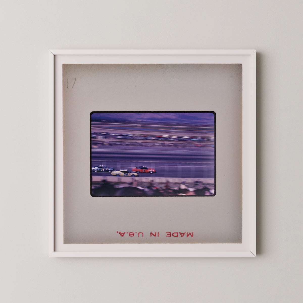 The image is a framed photograph of a race track with blurred cars on the track.