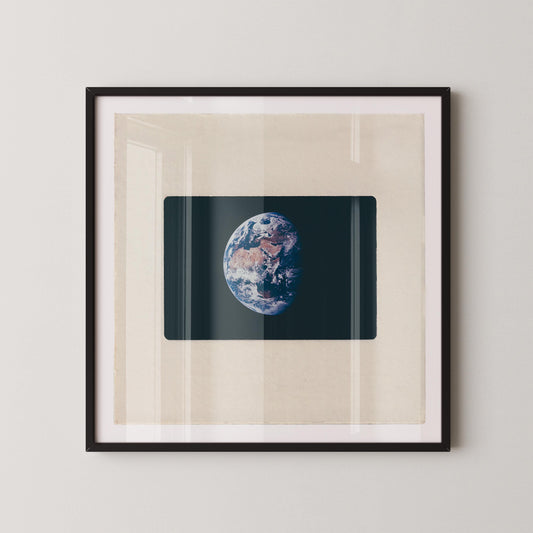The image is a framed photograph of the Earth, depicting the planet's surface and atmosphere.