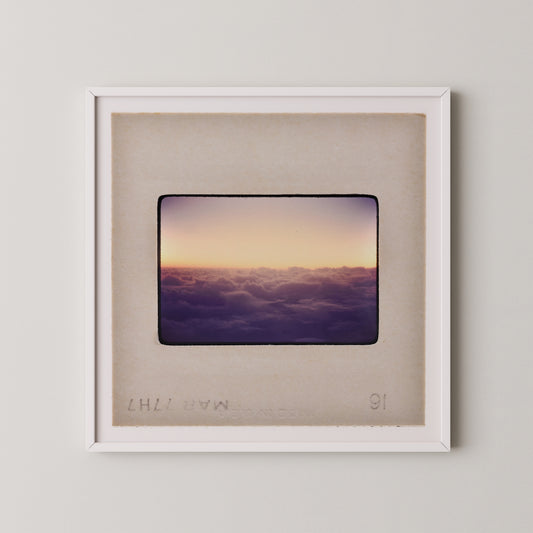 The image is a framed photograph of a sunset over a cloudy sky.