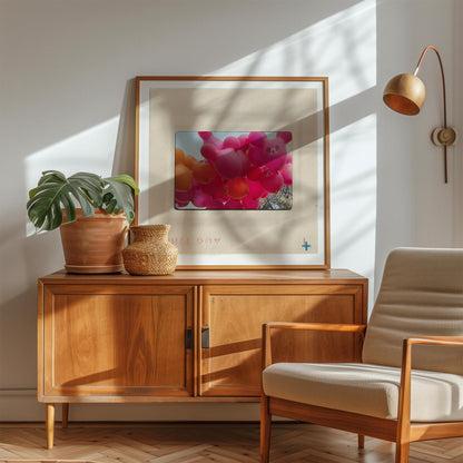 a cozy living room with a wooden cabinet, a comfortable chair, and a framed picture of pink balloons on the wall.