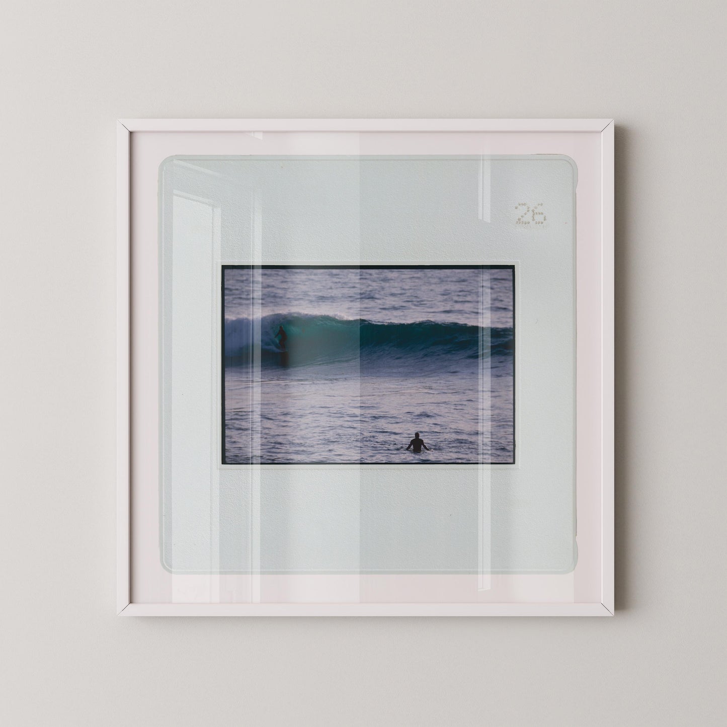 Vintage slide photograph of two surfers in the ocean — one riding a glassy teal-green wave in the background and one waiting chest-deep in silver-grey water in the foreground, shot with a telephoto lens from shore. Printed as a giclée fine art print on archival matte paper.