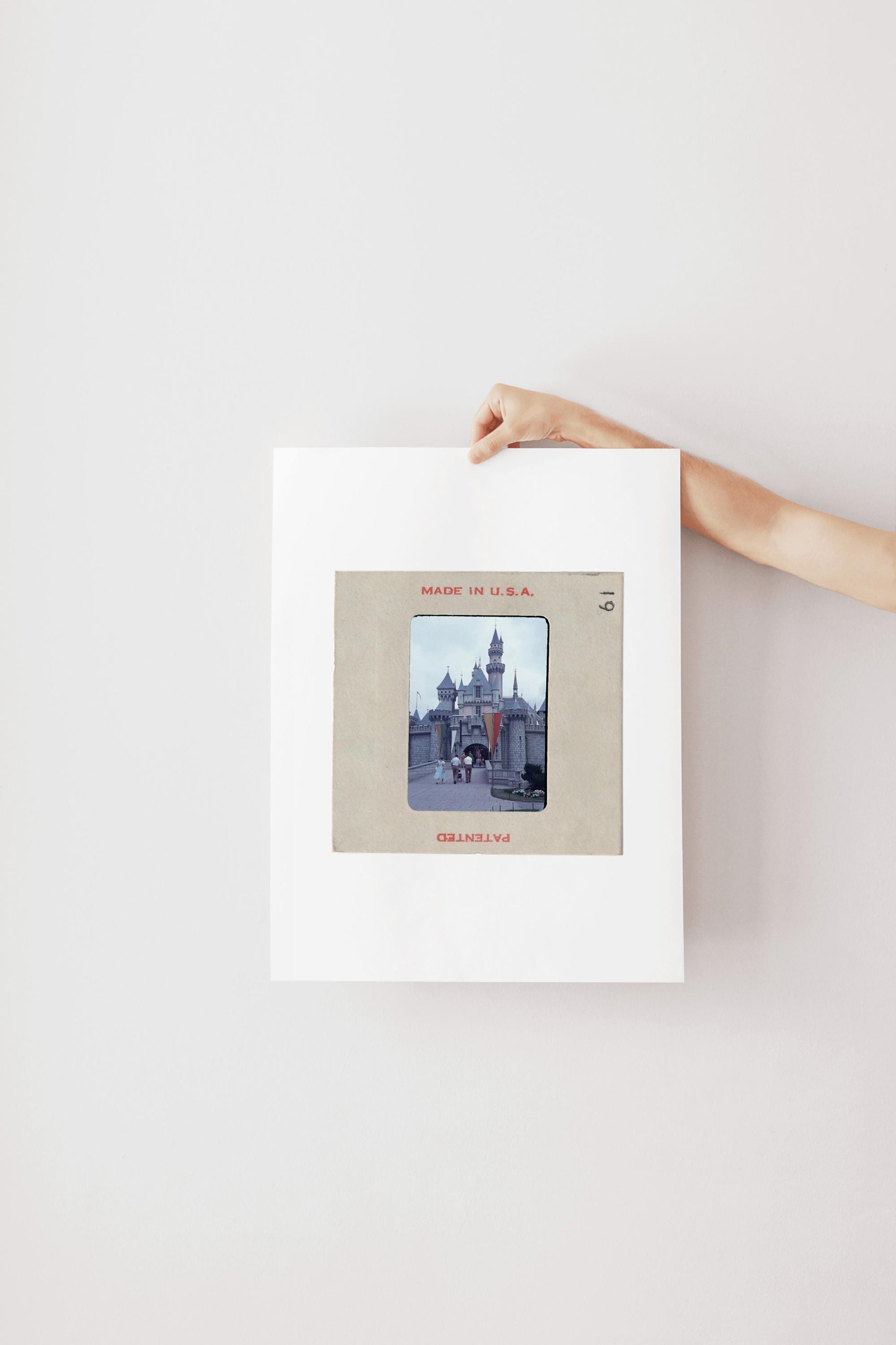A person's hand is holding a framed photograph of a castle or palace, with the text "MADE IN U.S.A." visible on the frame.