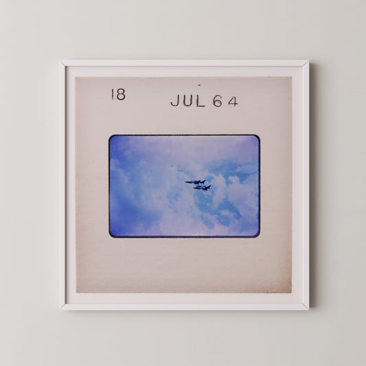 The image is a framed photograph of two airplanes flying in the sky, with the date "18 JUL 64" written above it.